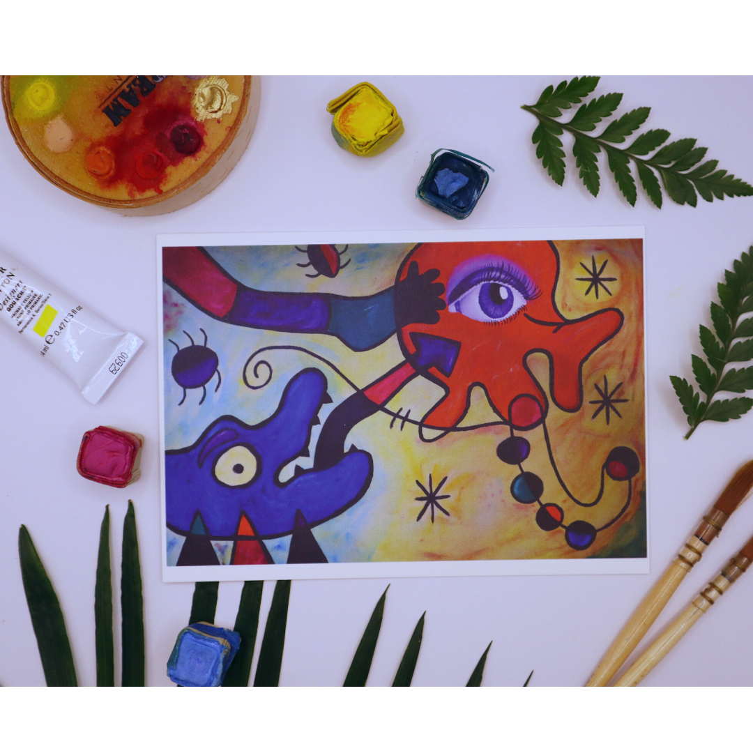 Photo of sbstract acrylic with a detailed purple eye. Watercolour paletters and greenery surrounding art print with paint brushes and other painting tools